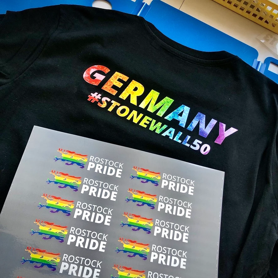 Schwarzes Shirt mit farbigem Germany-Motiv und vorbereiteten Rostock-Pride-Motiven